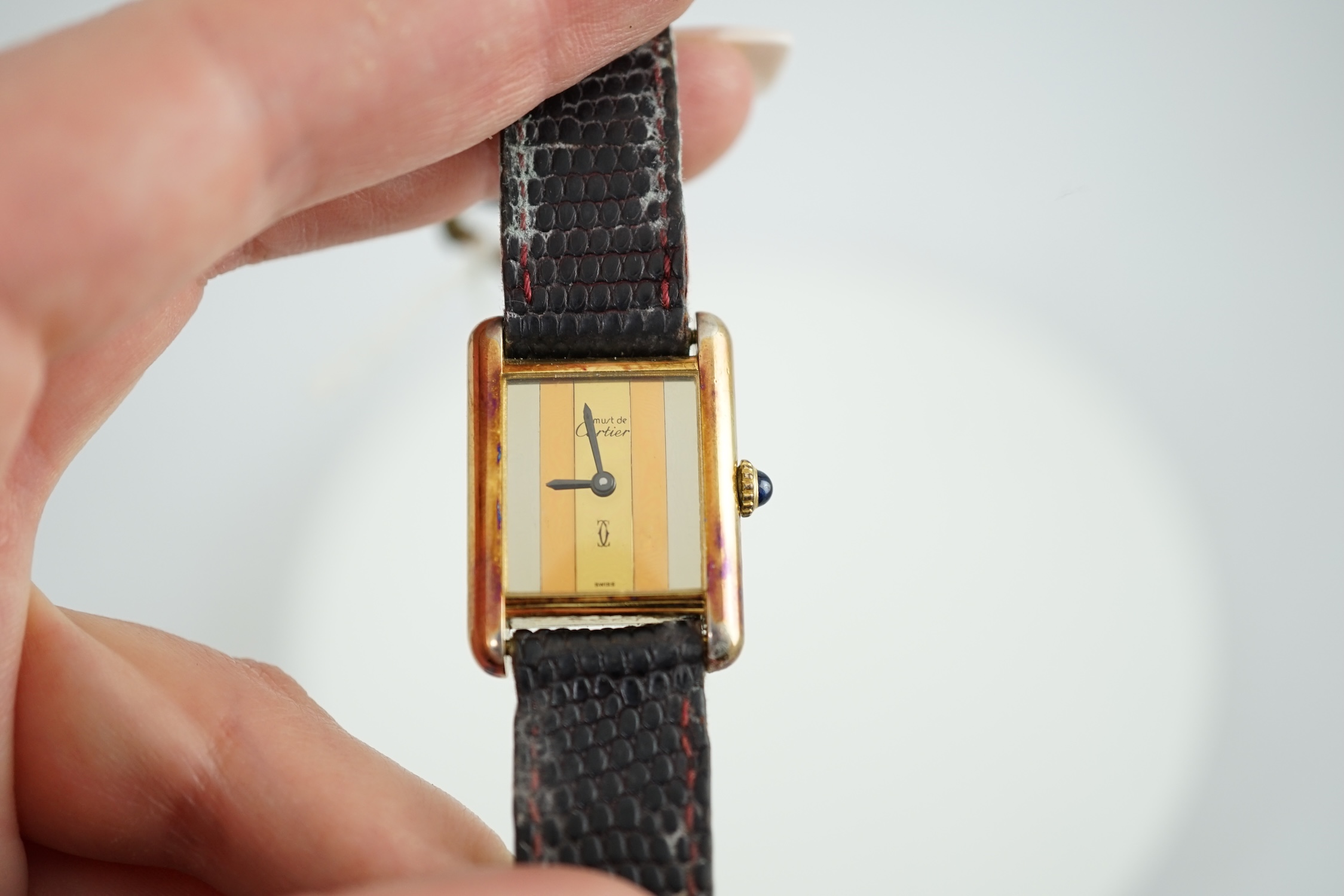 A lady's silver gilt Must De Cartier rectangular dial manual wind wrist watch, case diameter 20mm, on a leather strap.